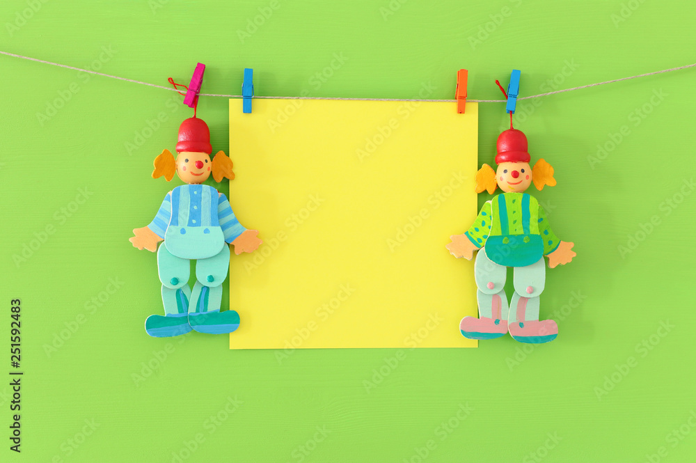 Purim (jewish carnival holiday) and party celebration concept with empty note for text and cute clowns wooden green background