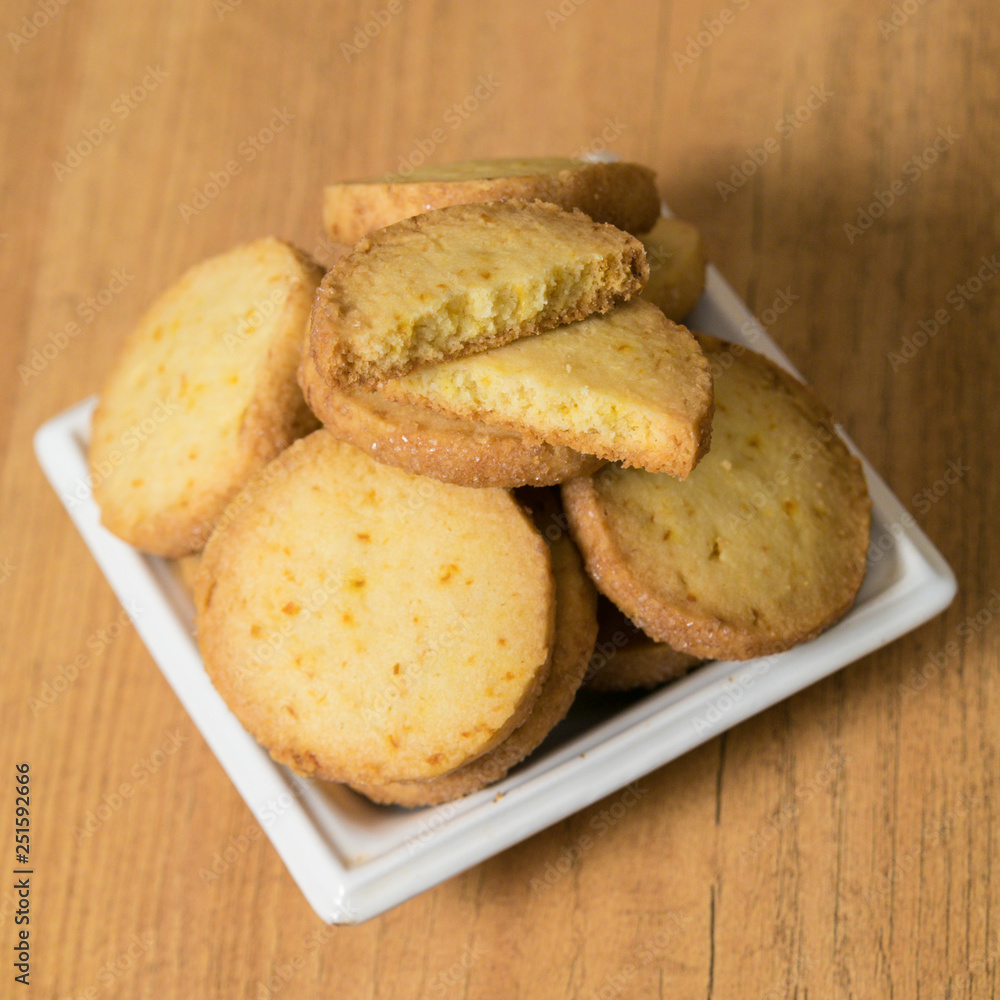 Homemade lemon cookies in a white saucer on a wooden table. Square picture, closeup. Homemade lemon cookies in a white saucer on a wooden table. Square picture, closeup.
