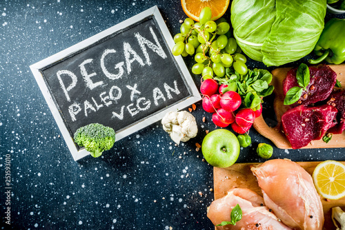 Trendy pegan diet - vegan plus paleo diet food concept, many fresh vegetables, fruits, raw beef and chicken meat, salmon fish, dark blue background top view copy space