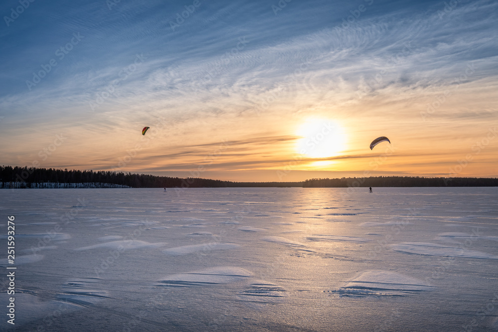 Kite skiing on frozen lake with beautiful sunset at winter evening in Finland