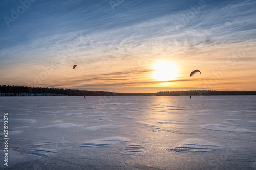 Kite skiing on frozen lake with beautiful sunset at winter evening in Finland