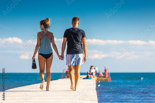 Young couple is walking on the pier during sunset
