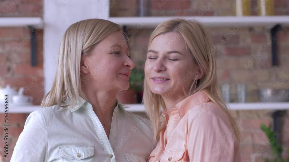 mother kiss, portrait of beautiful family mom and adult daughter smiling and looking at camera close-up indoor mother kiss, portrait of beautiful family mom and adult daughter smiling and looking at camera close-up indoor