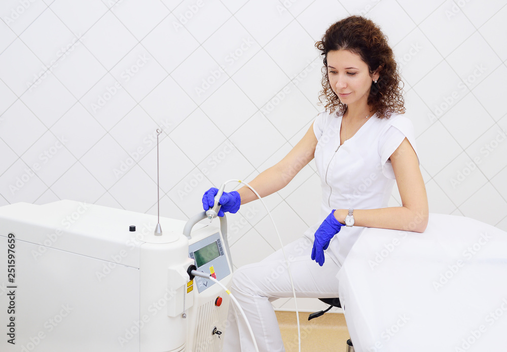 girl cosmetologist on the background of a laser apparatus or installation for aesthetic medicine. Peeling, rejuvenation, lifting, removal of moles, vascular nets, dermoabrasion. girl cosmetologist on the background of a laser apparatus or installation for aesthetic medicine. Peeling, rejuvenation, lifting, removal of moles, vascular nets, dermoabrasion.