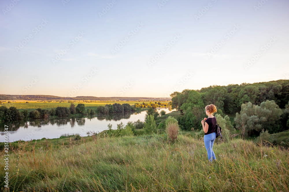 The young girl contemplates the beauty of nature. The girl from the hill looks at the river and the forest_