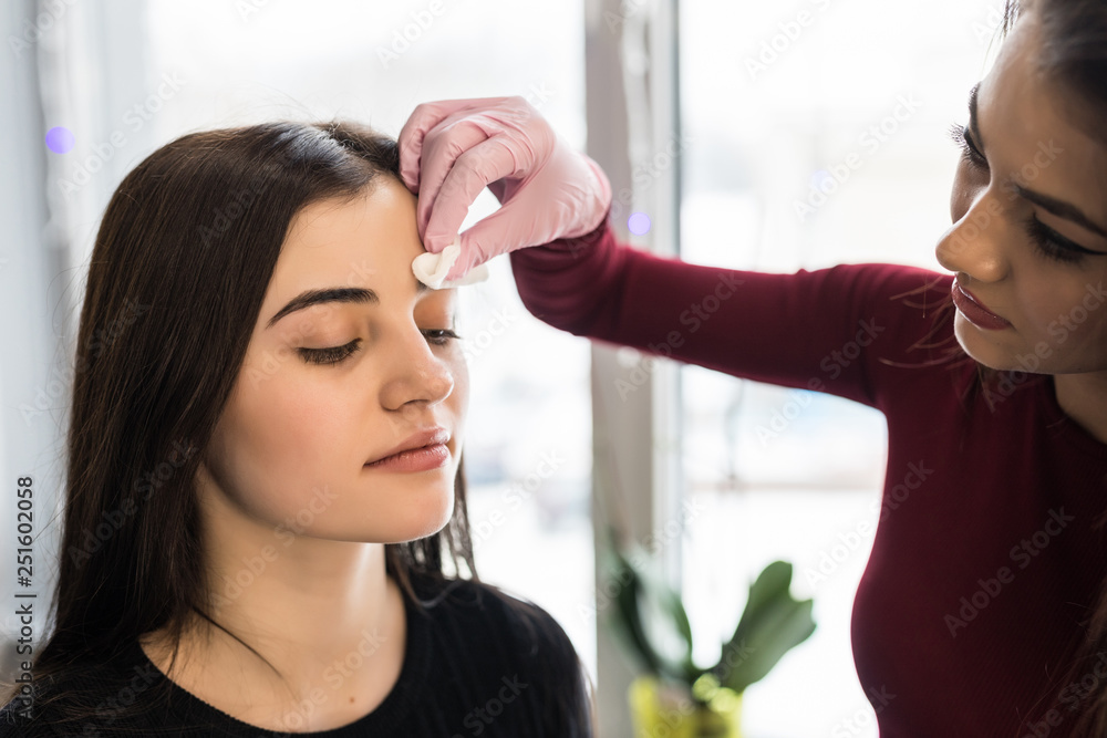 Fototapeta premium Master corrects makeup, gives shape and thread plucks eyebrows in a beauty salon. Professional care for face.