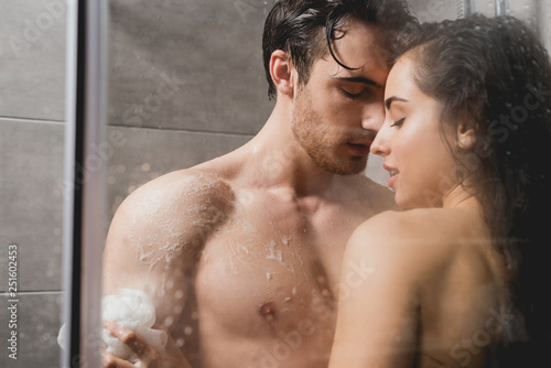 man and woman hugging and taking shower with loofah in cabin photo