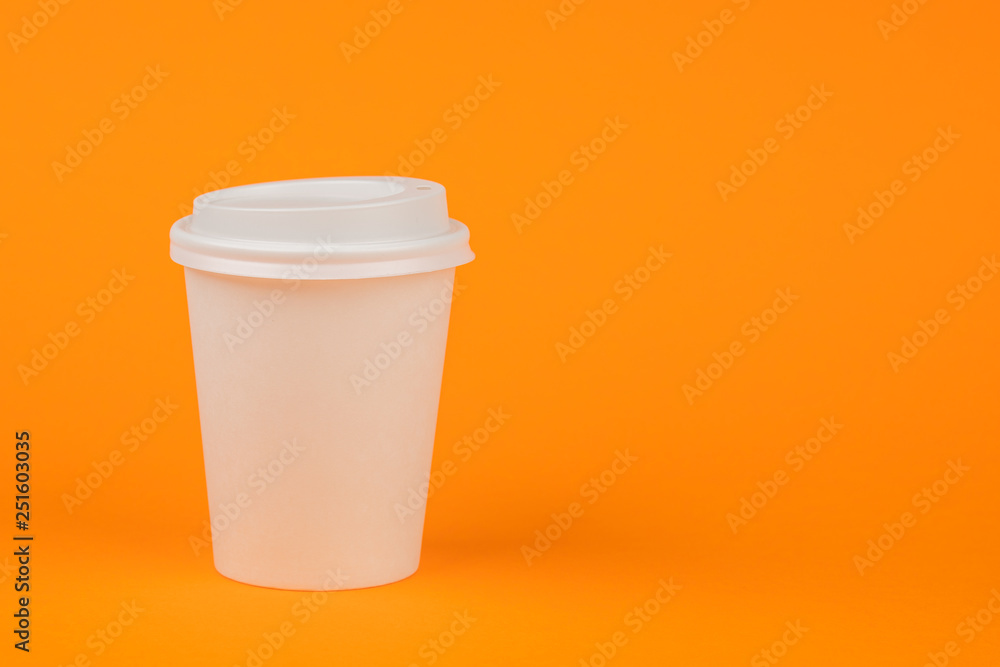 Paper container for coffee with a white cap on an orange background. Take-away beverage container. Drink Cup template for your design Paper container for coffee with a white cap on an orange background. Take-away beverage container. Drink Cup template for your design