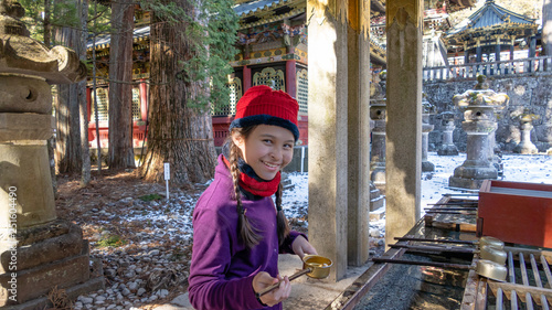 Tween mixed race girl by Japanese purification basin at temple