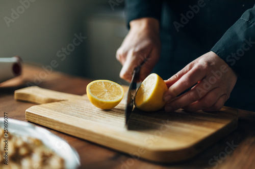 Chef cutting lemons on a wooden board