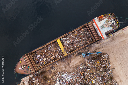 Drone aerial view loading in ship holds scrap metal for transportation. Collection of metal for secondary raw materials. Metallic trash for recycling. Black scrap, color scrap. Scrap import and export photo