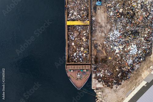 Drone aerial view loading in ship holds scrap metal for transportation. Collection of metal for secondary raw materials. Metallic trash for recycling. Black scrap, color scrap. Scrap import and export