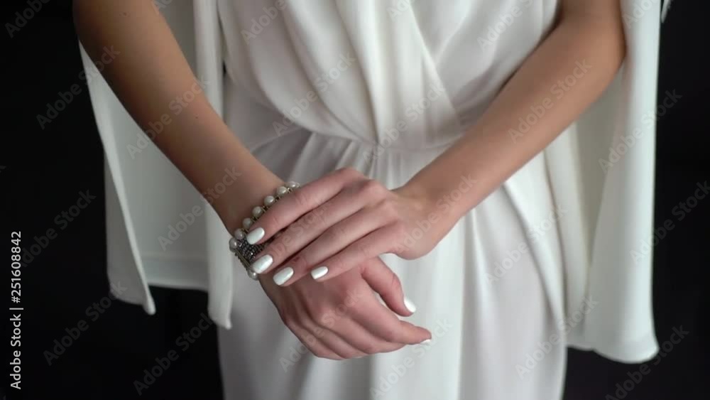 Bride in white wedding dress put on bracelet on her hand Bride in white wedding dress put on bracelet on her hand
