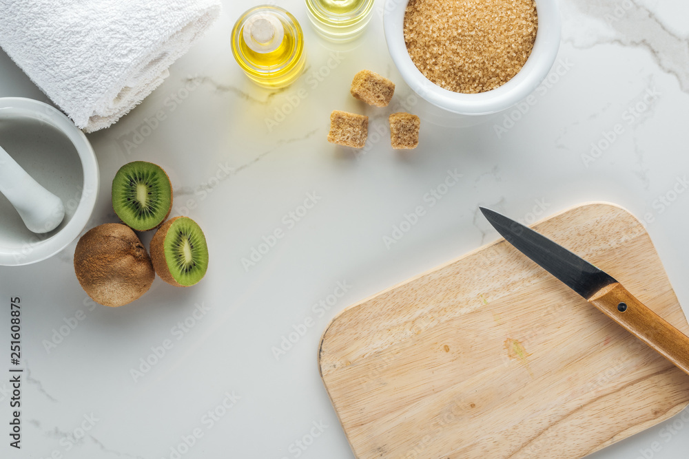 top view of various natural ingredients for cosmetics making, and cutting desk with kiwi on white surface top view of various natural ingredients for cosmetics making, and cutting desk with kiwi on white surface