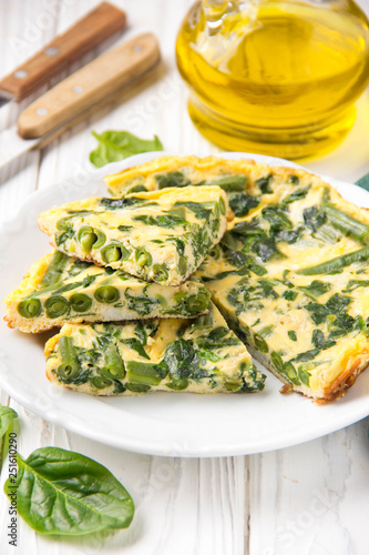 Omelet with spinach and green beans, healthy food. Egg and milk Frittata, delicious Breakfast on white wooden background