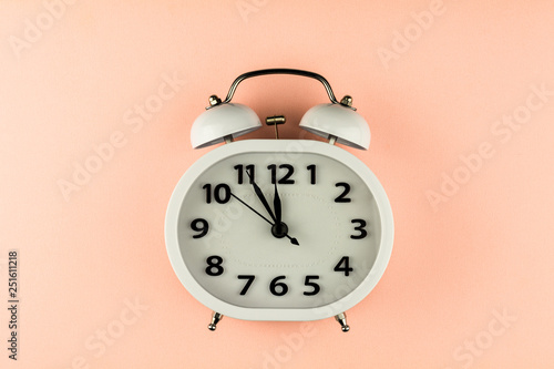 white vintage alarm clock on pink background. - top view.