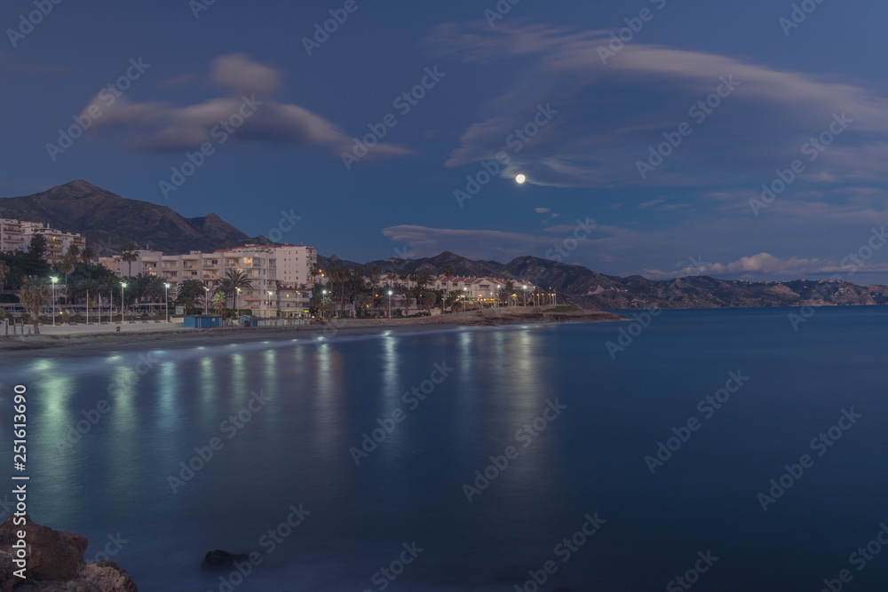 Nerja, Malaga, Andalusi, Spain - January 19, 2019: Moon at the beginning of the night over the coastal town of Nerja, southern Spain