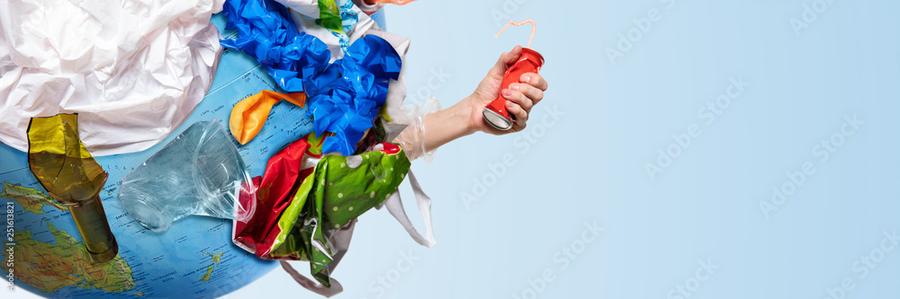 An earth globe covered with trash and male hand squeezing aluminum can over white background, the concept of ecology problem and World Environment Day. Photo with message for social advertising, place