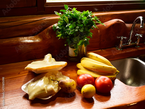 en una cocina rustica se observan varias frutas bananas, peras, tomates y carne photo