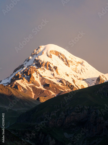 Mount Kazbek in the Republic of Georgia  Caucasus  at sunrise  seen from the Gergeti Trinity Church. Horizontal   landscape orientation  purple early morning sky in the background. 