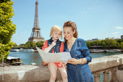 happy stylish mother and daughter travellers looking at map photo