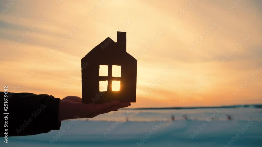 Silhouette hand with paper house at sunset background. Silhouette hand with paper house at sunset background.