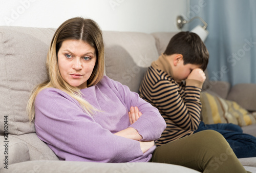 Upset mother and offended son crying after quarrel at home