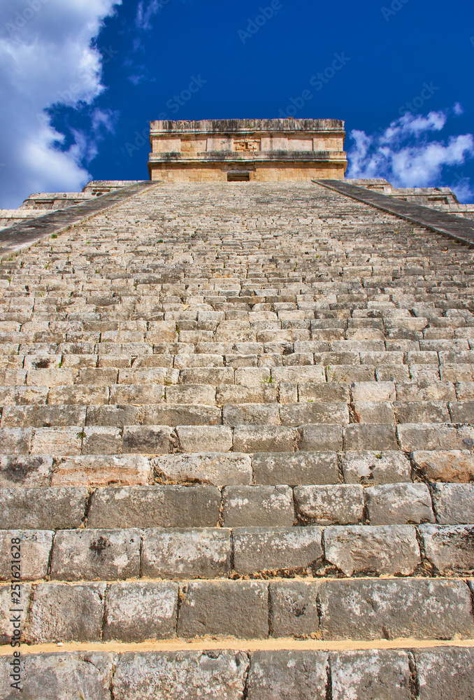 Sunny day with blue sky and white clouds. No people around. Detail for stairs going to the top. El Castillo (The Kukulkan Temple) of Chichen Itza, mayan pyramid in Yucatan, Mexico- Mar 2, 2018