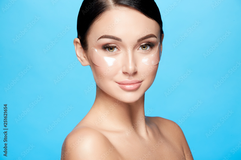 Perfect girl with nude make up and naked shoulders at studio background, invisible eye patches on face, skin care concept, looking at camera Perfect girl with nude make up and naked shoulders at studio background, invisible eye patches on face, skin care concept, looking at camera