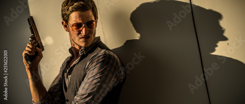 Young Caucasian male holding a gun in a sunset hotel