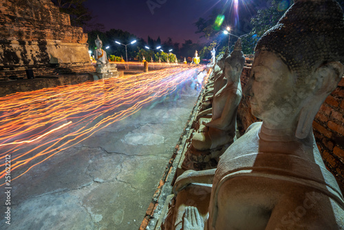 Buddhists people walking with lighted candles in hand around a ancient temple photo
