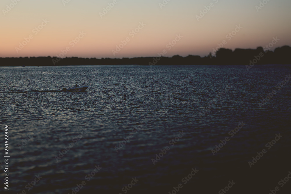 The boat floats on the river in the late evening
