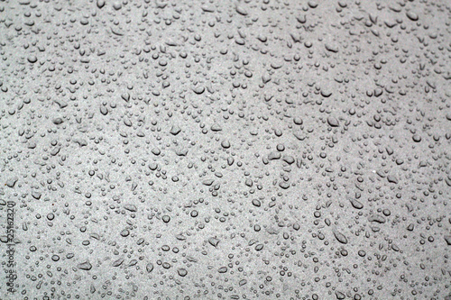 Water drops on grey car surface.