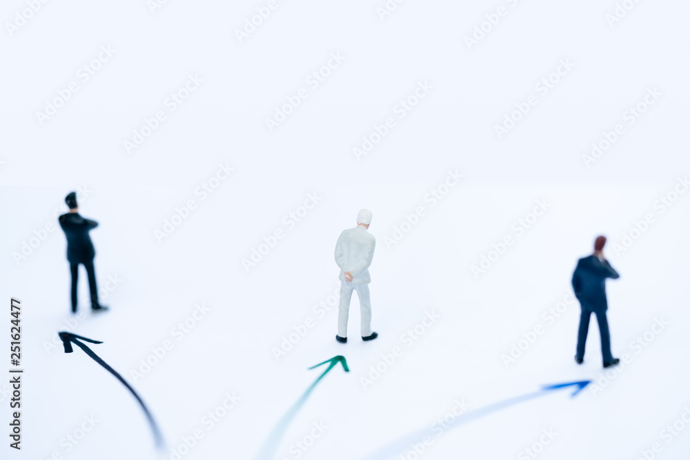 Miniature people: Small businessman figures standing on turning poing. The concept of role conflict in society and at home. Miniature people: Small businessman figures standing on turning poing. The concept of role conflict in society and at home.