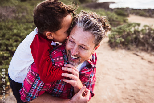 Smiling father carrying his son piggyback outdoor