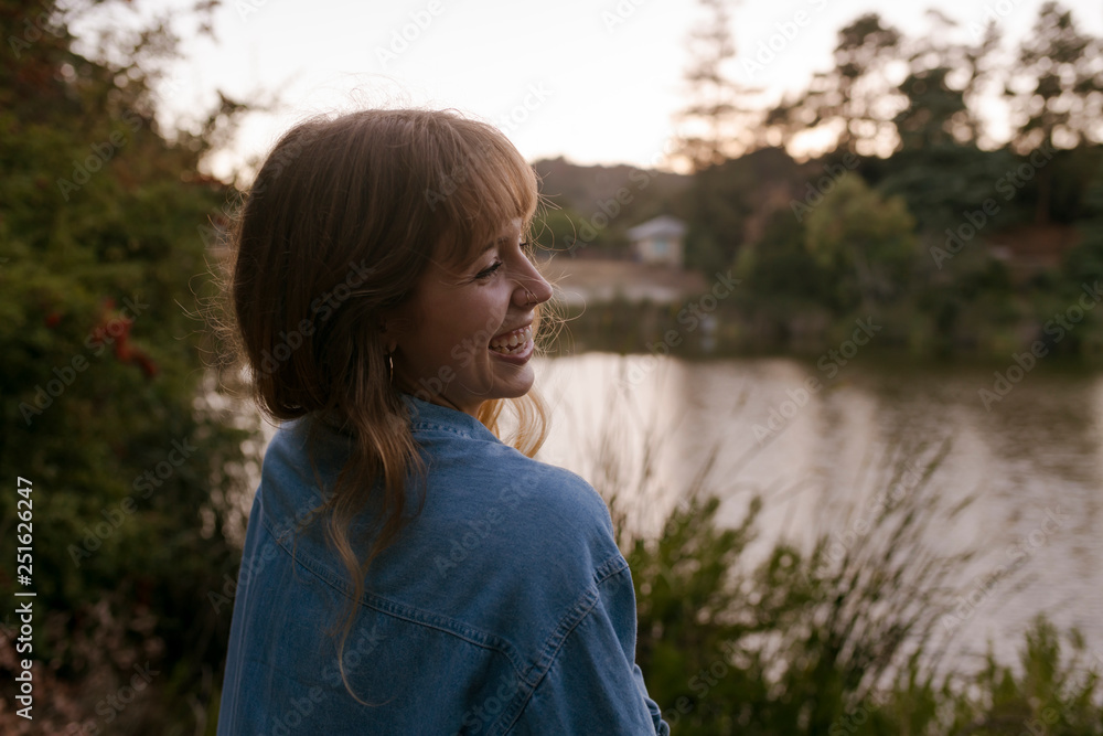 Smiling young woman standing near lake Smiling young woman standing near lake