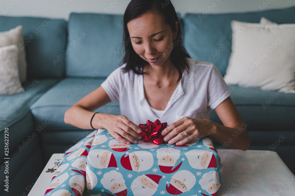 Woman wrapping Christmas gift while sitting at home Woman wrapping Christmas gift while sitting at home