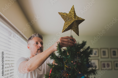 Man decorating Christmas tree at home