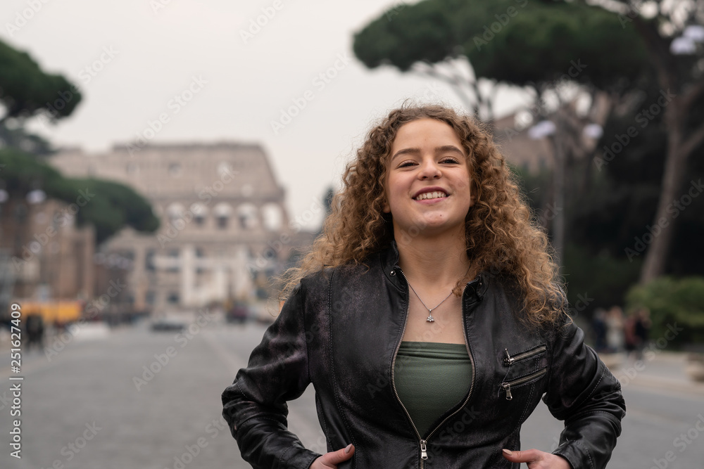 Happy young woman enjoys her visit to Rome, Italy, in front of the coliseum