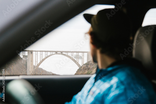 Man looking at bridge while sitting in car