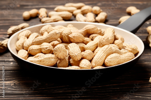 Roasted peanuts in a pan on a wooden background. Place for text.