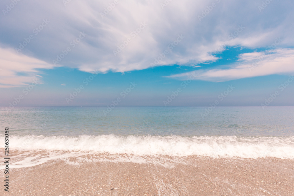 Idyllic seascape with surf line and beautiful clouds over sea. The sea foam at coastal line. Summer paradise beach.
