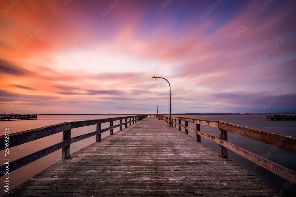 Beautiful colorful clouds streaking over a pier at sunset. Dramatic coastal scene with no people. Long Island New York. 