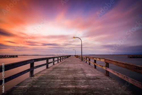 Beautiful colorful clouds streaking over a pier at sunset. Dramatic coastal scene with no people. Long Island New York. 