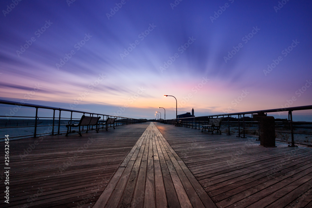 Moody empty boardwalk at dusk. Dramatic scene with blue tones and wispy sweeping clouds 