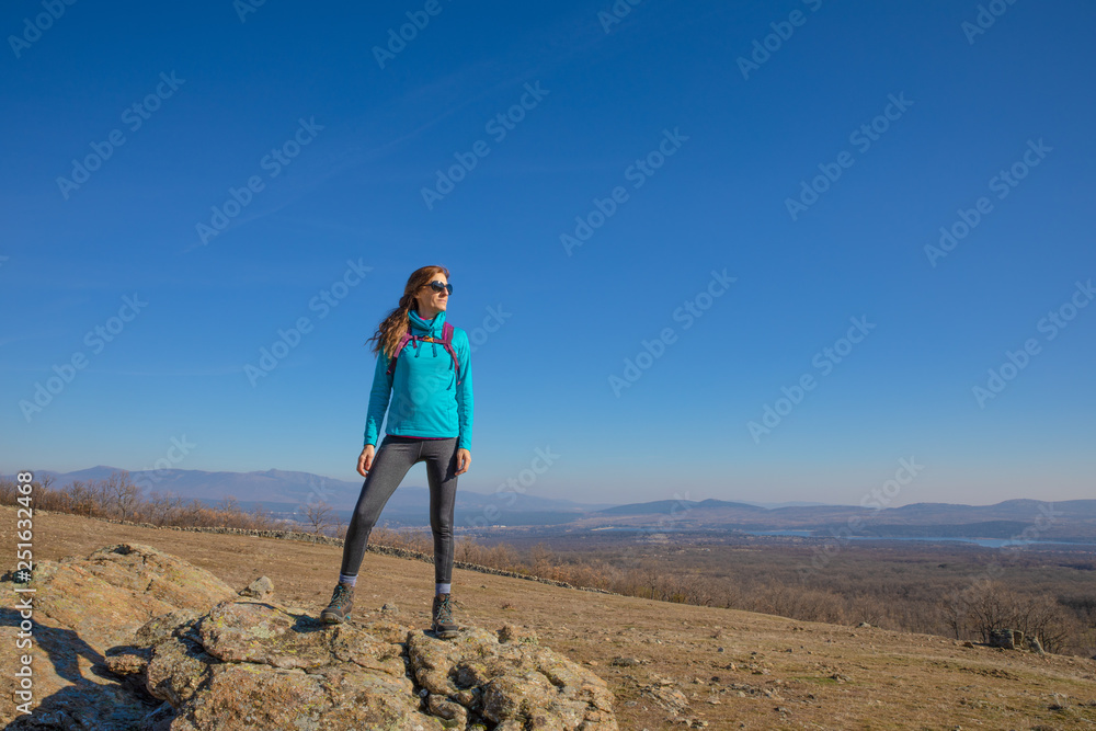 sport hiking or trekking woman standing on rock, looking at copy space, in Guadarrama Natural Park (Madrid, Spain)