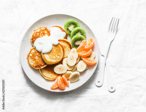 Delicious breakfast or snack - pancakes with fruit and sour cream on a light background, top view. Baby food