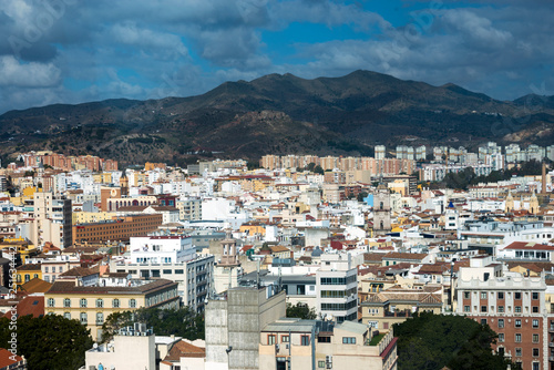 View of the Spanish city of Malaga from a height. Residential buildings, mountains, sights on the background of a cloudy sky. © Лариса Люндовская