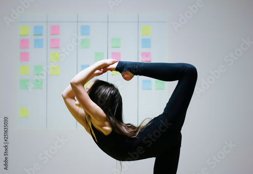 Girl symbolizes flexibility of agile project management approach: she is doing gymnastics element on the background of scrum task board photo