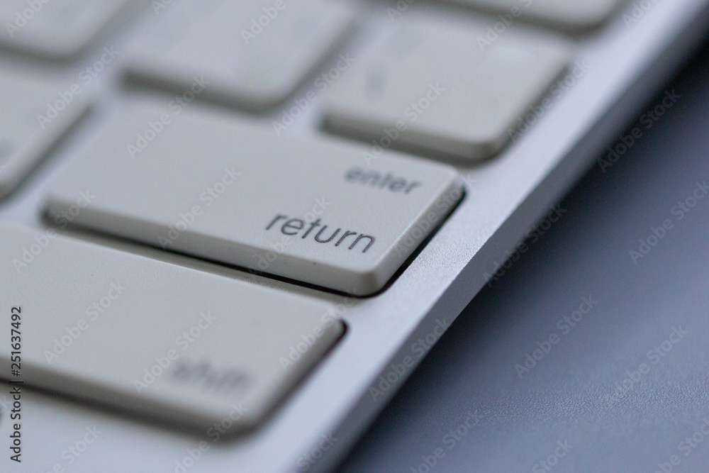 Wireless keyboard on gray background. Which is a close-up angle focusing on the Return or Enter button Wireless keyboard on gray background. Which is a close-up angle focusing on the Return or Enter button